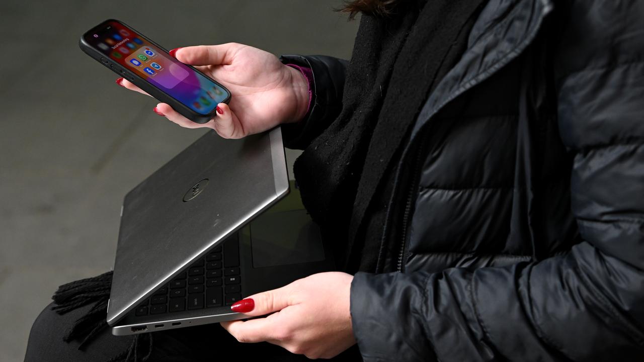 Person holds mobile phone and laptop
