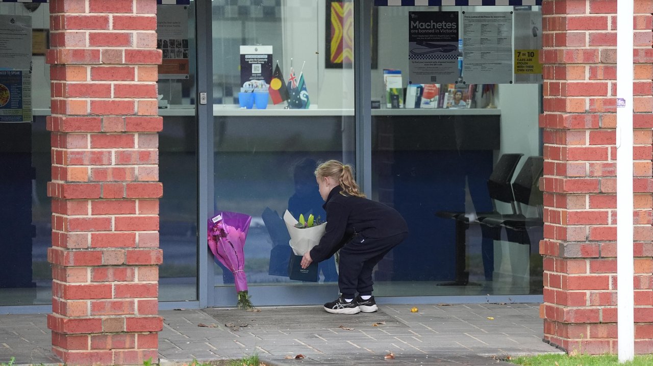 A girl placing a flower tribute at the Myrtleford Police station