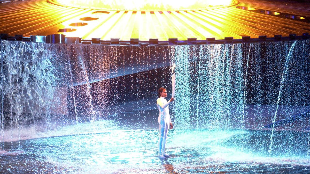 Cathy Freeman stands beneath the Olympic flame