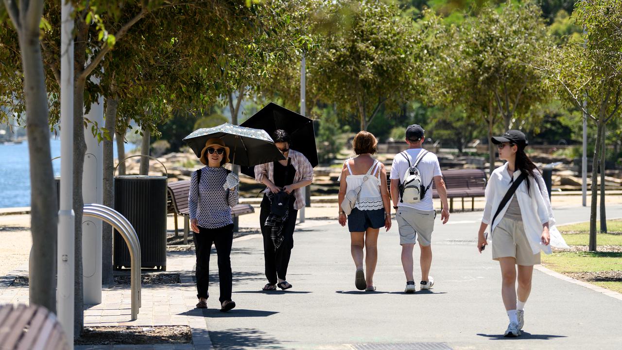 Sydneysiders use umbrellas to shield themselves from the sun