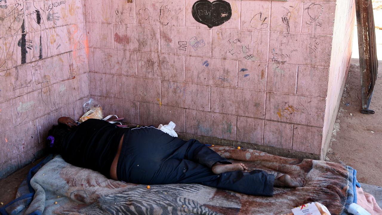 An Aboriginal woman sleeps outside at a camp near Alice Springs (file)