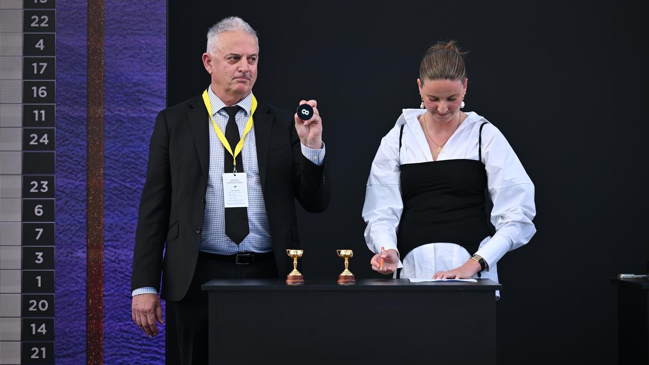 A representative of Melbourne Cup horse Half Yours holds No.8.