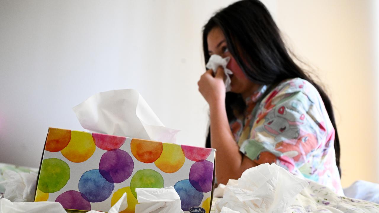A woman lows her nose into tissues