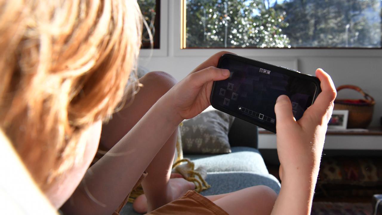 A boy plays Minecraft on a phone