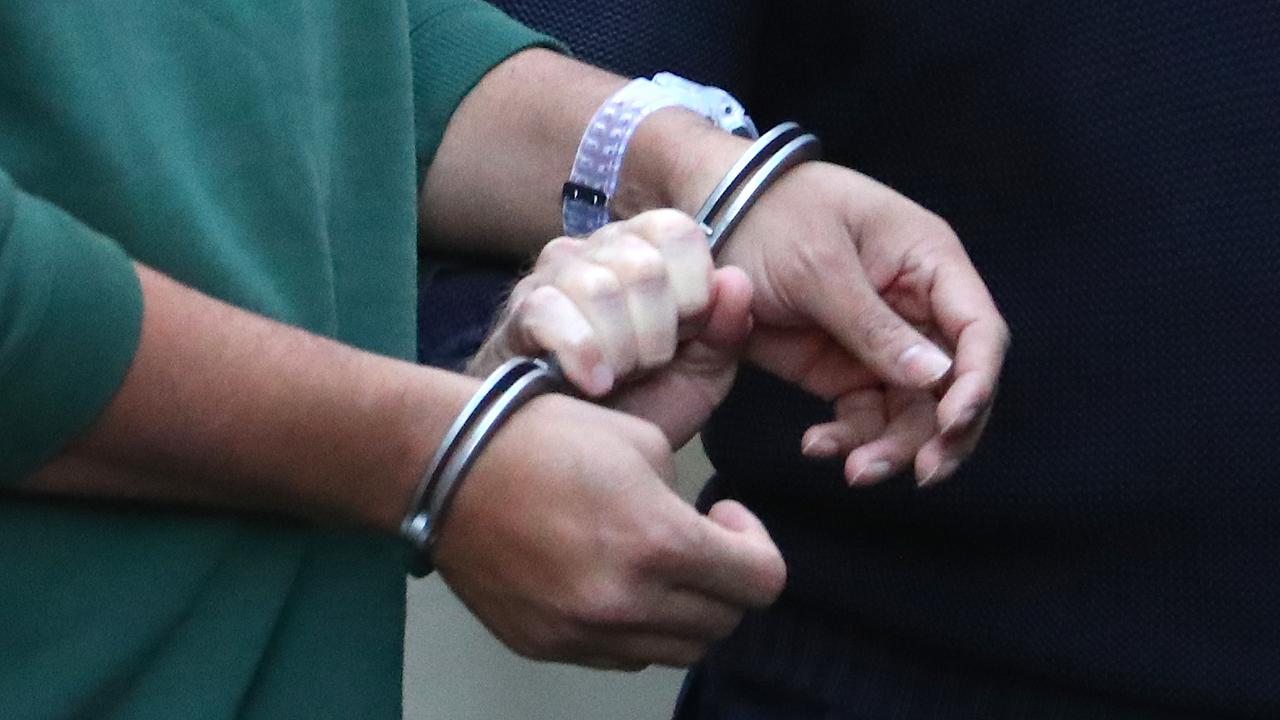 A prisoner is led by handcuffs