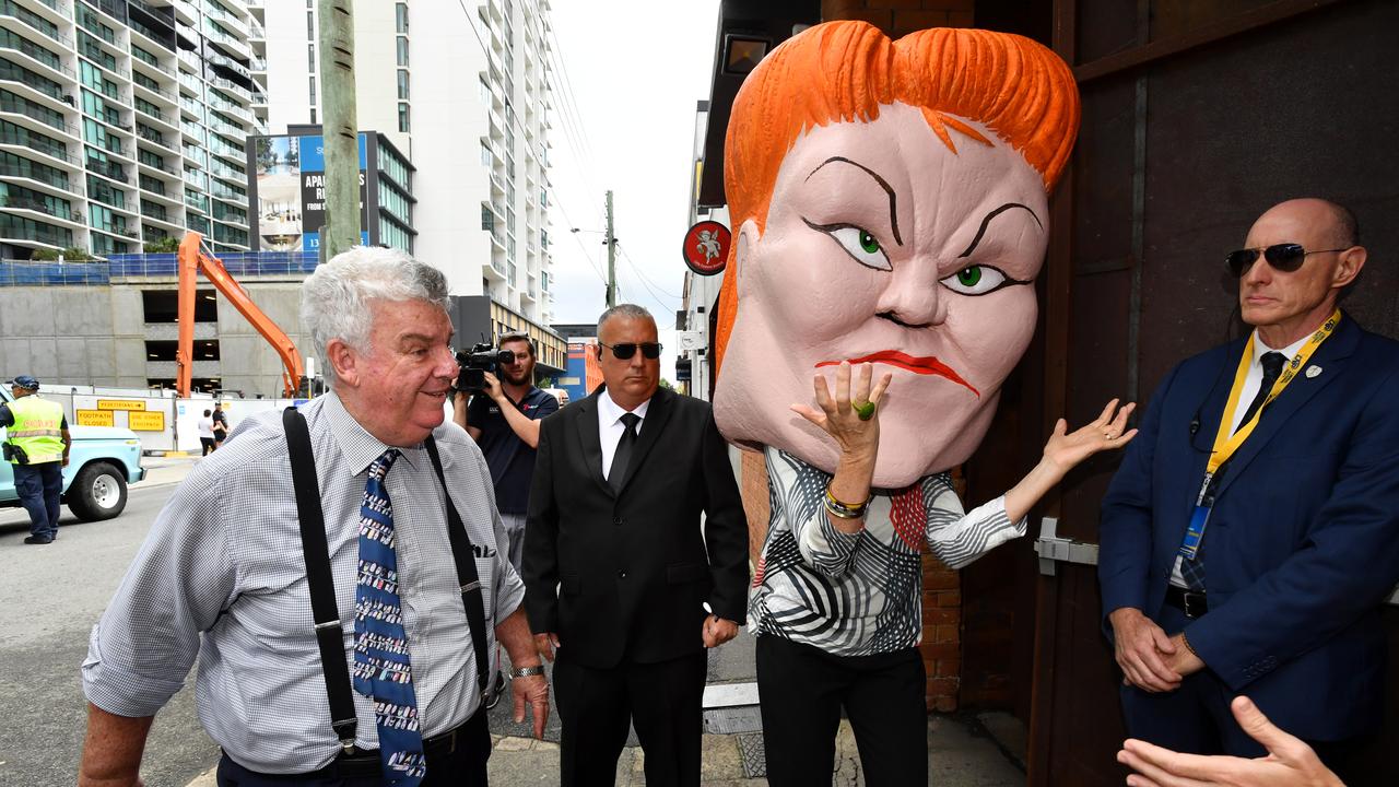 Ron Boswell walking past a protester wearing a Pauline Hanson mask