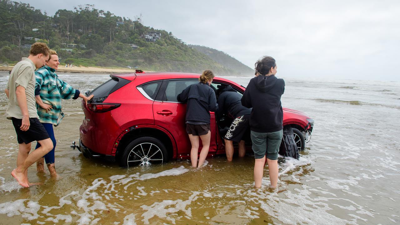 People enter the water to recover belongings from a vehicle