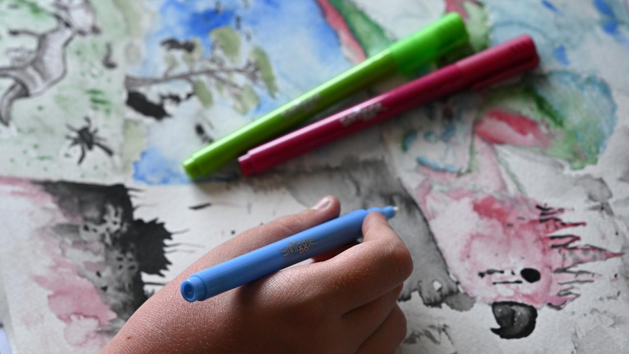 A child's hand is seen drawing