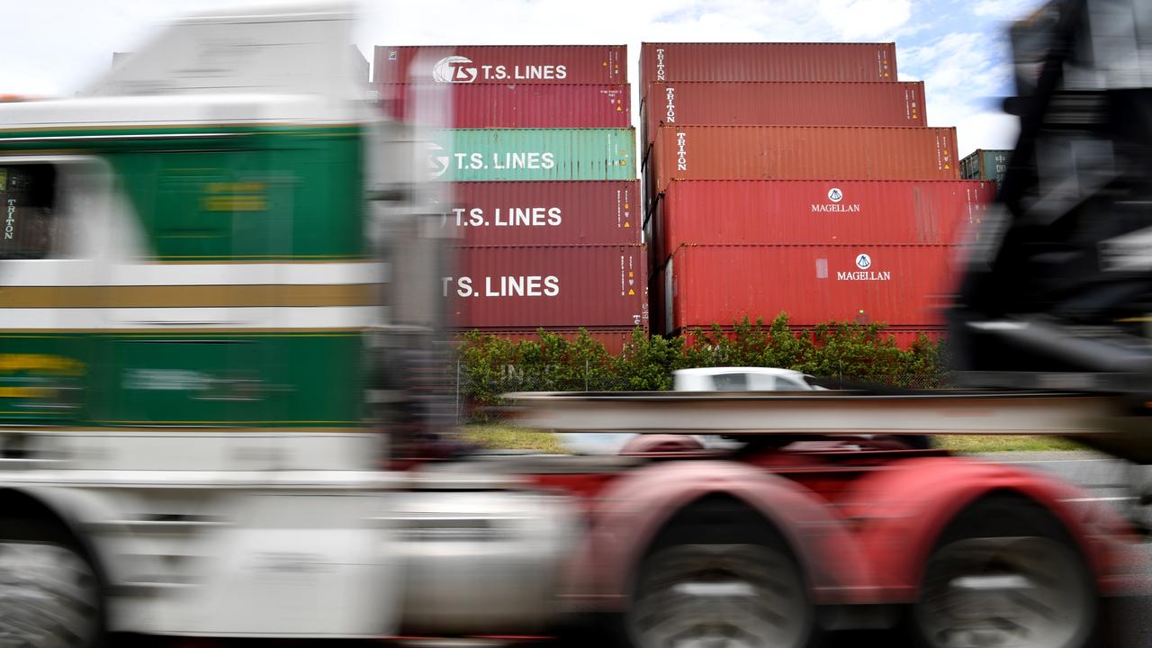 A truck is seen driving past a row of shipping containers