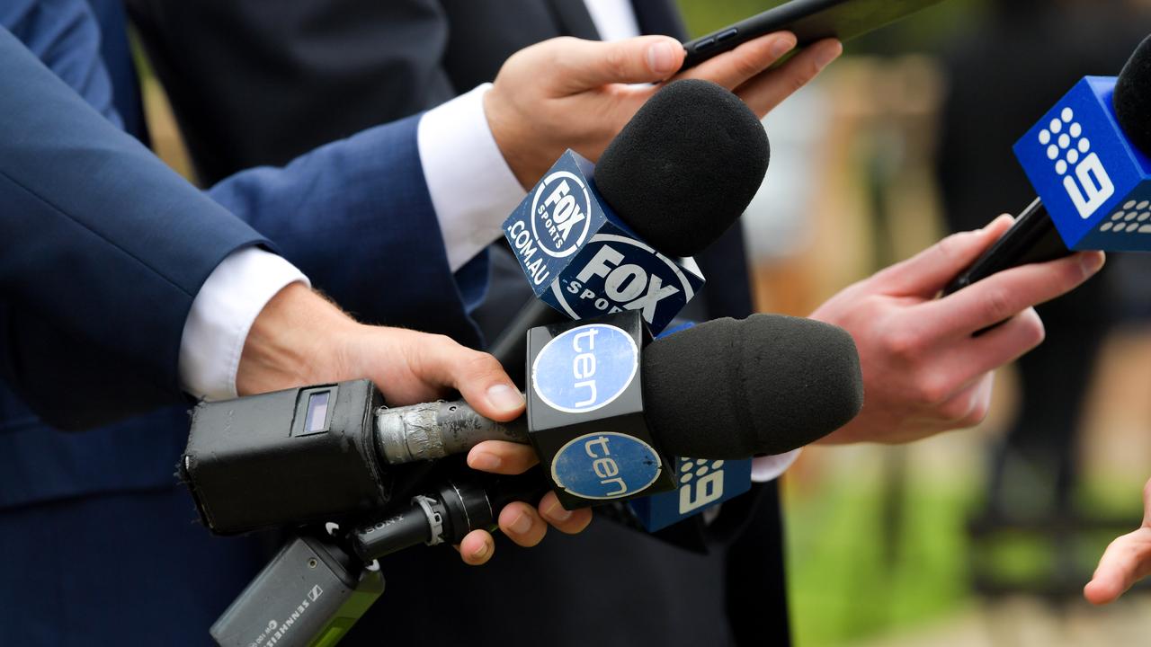 Reporters holding microphones at a press conference
