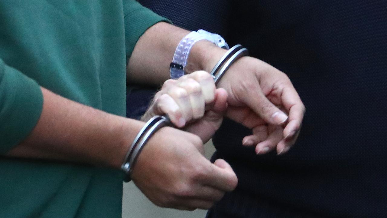 A prisoner is led by handcuffs (file image)