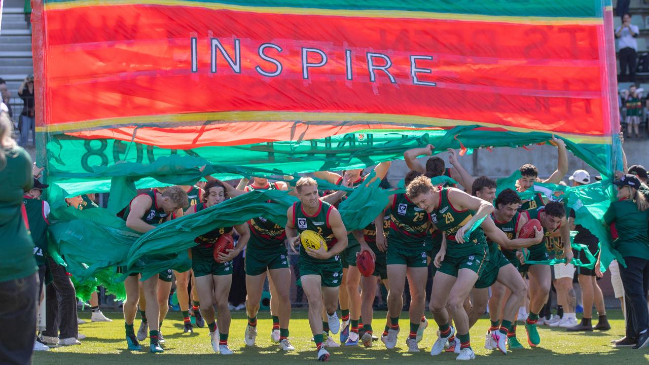 Tasmania Devils players run through the banner