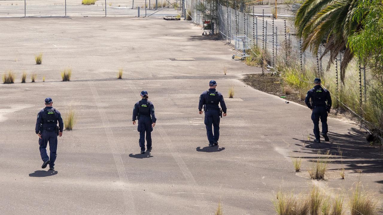 Police officers conduct a line search of a vacant lot