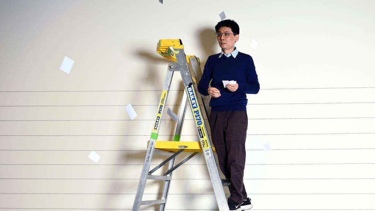 Ding on ladder with pieces of papers flying