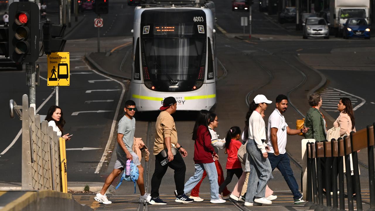 Pedestrians cross a road in front of a Yarra Tram