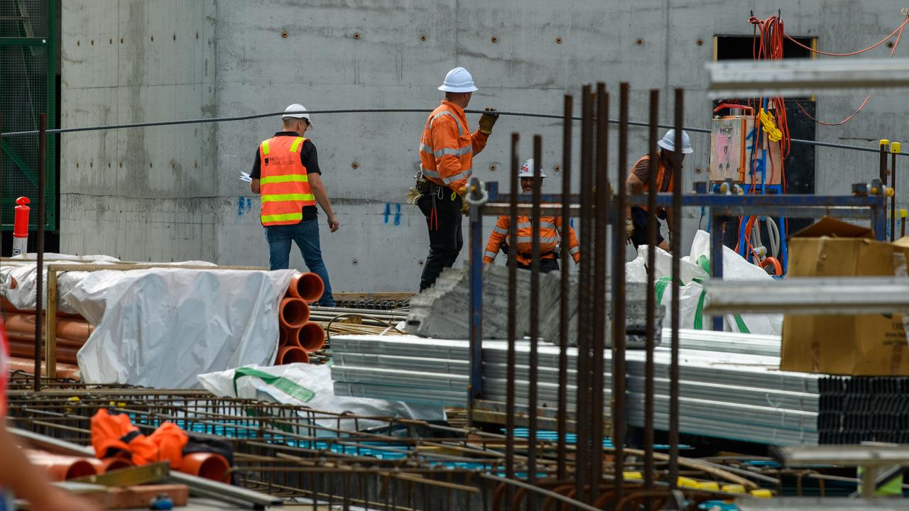 A construction worker carries a steel bar on a worksite
